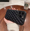 Black quilted phone case held by a hand on a wooden table with a Starbucks cup in the background.